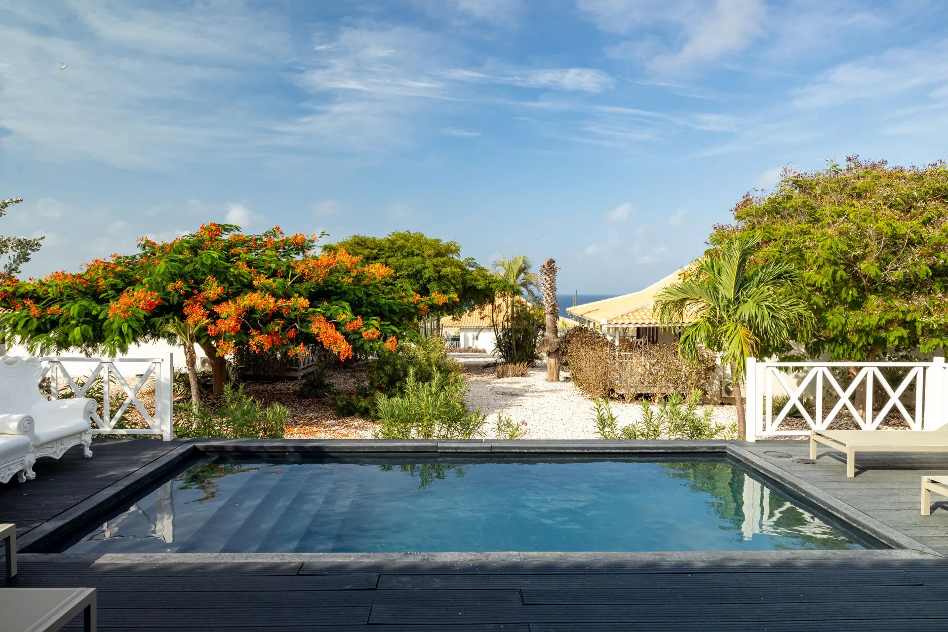Private pool at a Papagayo Resort villa surrounded by tropical gardens and colorful trees, with a view toward the sea.