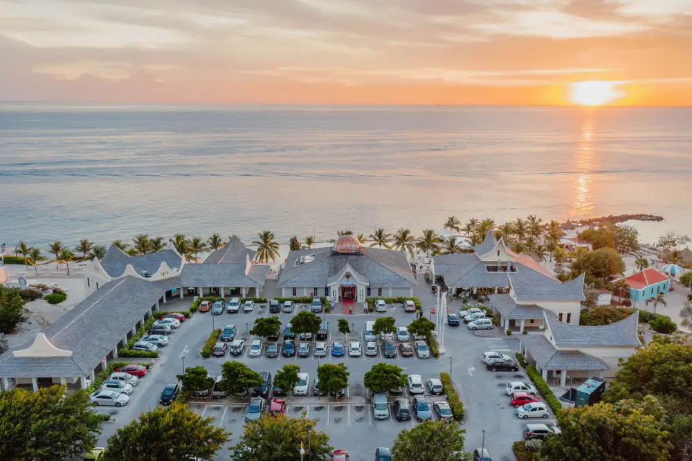 Aerial view of Papagayo Plaza at sunset, with a central dome building, surrounding shops, and palm-lined beachfront along the Caribbean Sea.