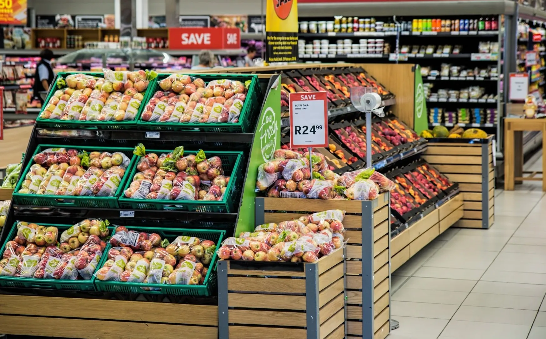 Papagayo Hotel Van den Tweel Supermarket Fresh produce section at Van den Tweel Supermarket in Papagayo Hotel, featuring neatly stacked apples in crates and a variety of groceries in the background.