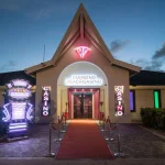 Entrance of Diamonds Beach Casino at Papagayo Beach, illuminated with neon lights and a red carpet walkway at dusk.