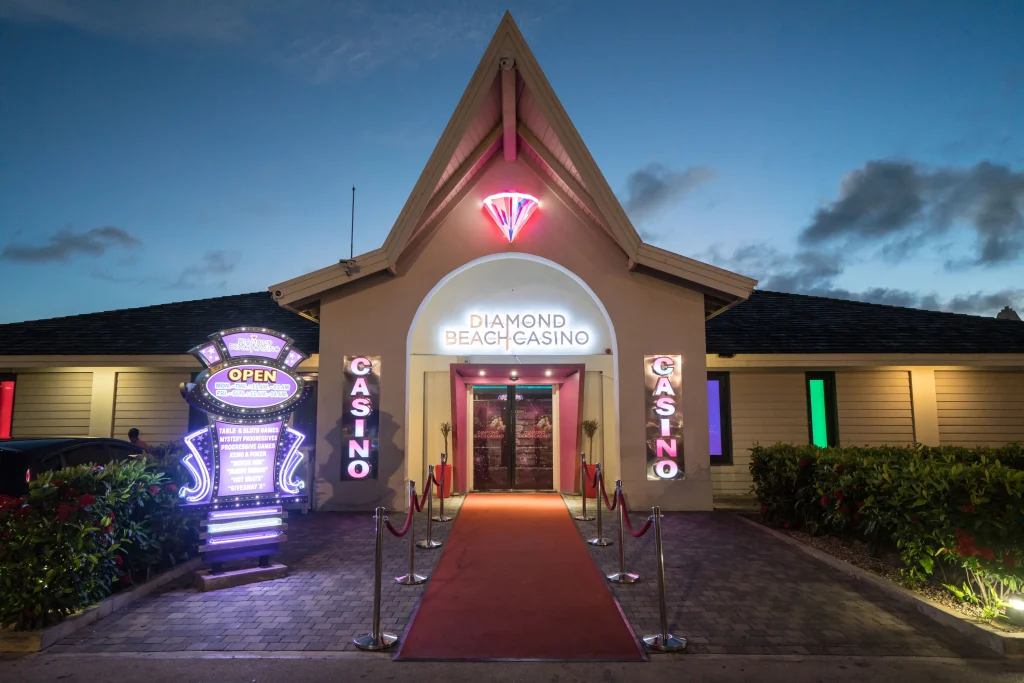 Entrance of Diamonds Beach Casino at Papagayo Beach, illuminated with neon lights and a red carpet walkway at dusk.