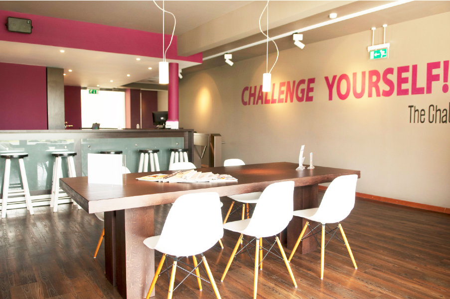 The Challenge Gym Papagayo Hotel Modern and welcoming gym reception area with white chairs, wooden floors, a long table, and the motivational phrase “CHALLENGE YOURSELF!” on the wall at The Challenge Gym.