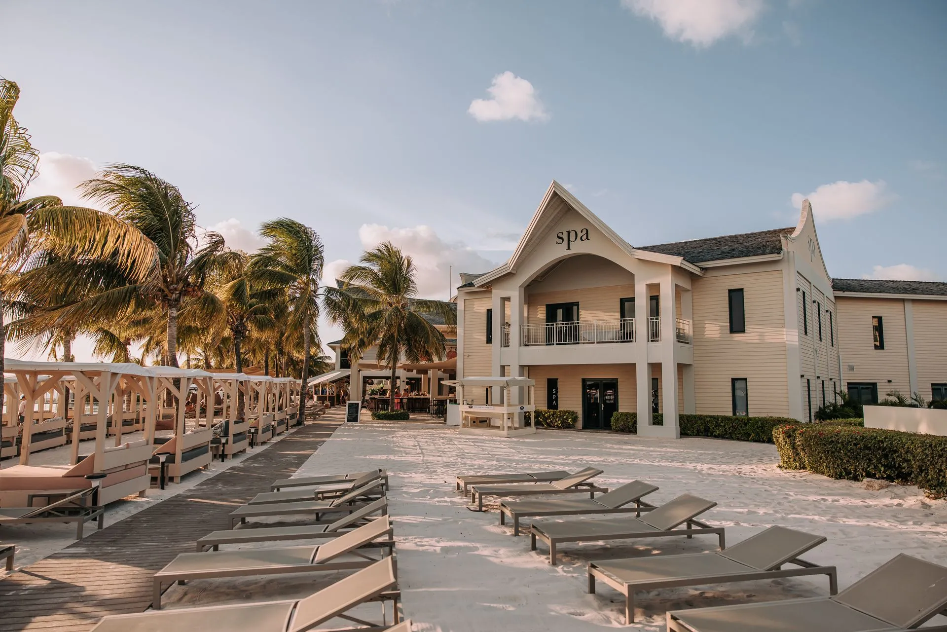 Papagayo Beach Club Spa Elegant beachfront spa building at Papagayo Beach Club in Curaçao, surrounded by palm trees, sun loungers, and shaded cabanas on soft white sand.