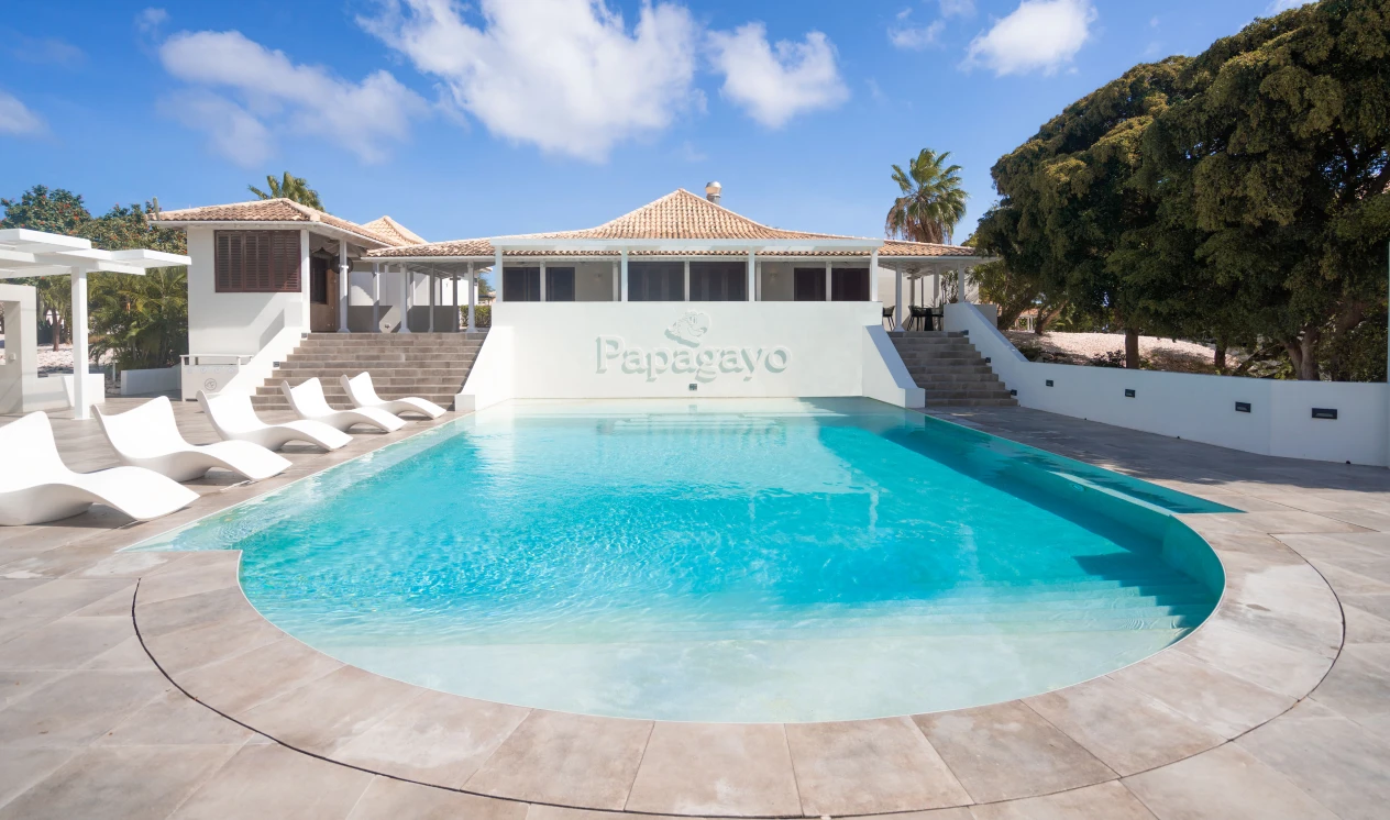 Elegant pool area at Papagayo Beach Resort with modern white loungers and tropical surroundings, perfect for a relaxing day under the sun.