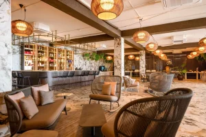 Stylish indoor hotel bar and lounge area with marble floors, modern furniture, and warm pendant lighting at Papagayo Beach Hotel