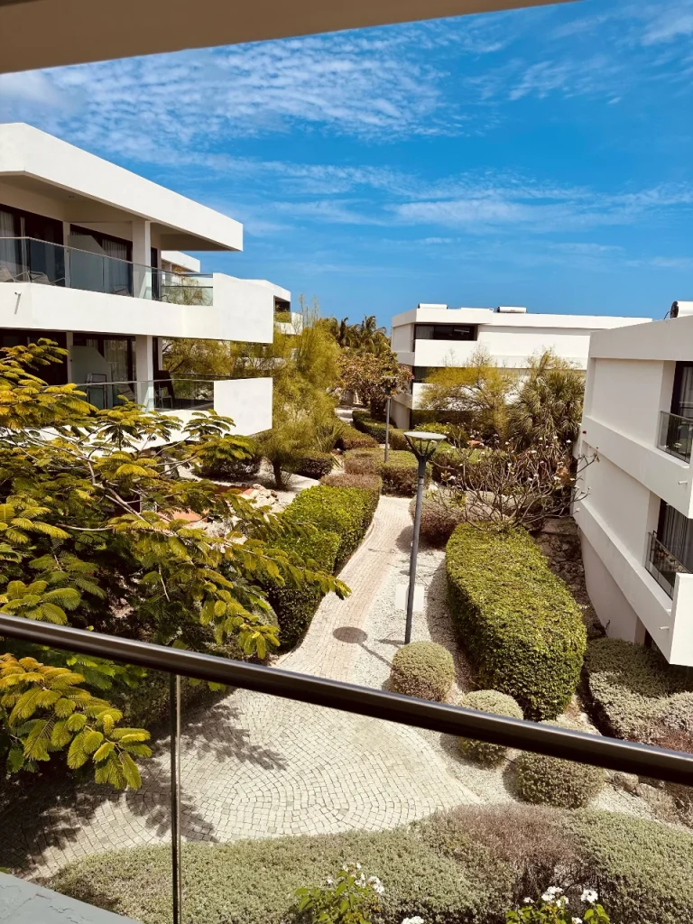Scenic view over manicured gardens, white modern buildings, and winding pathways at Papagayo Beach Hotel under a clear blue sky.