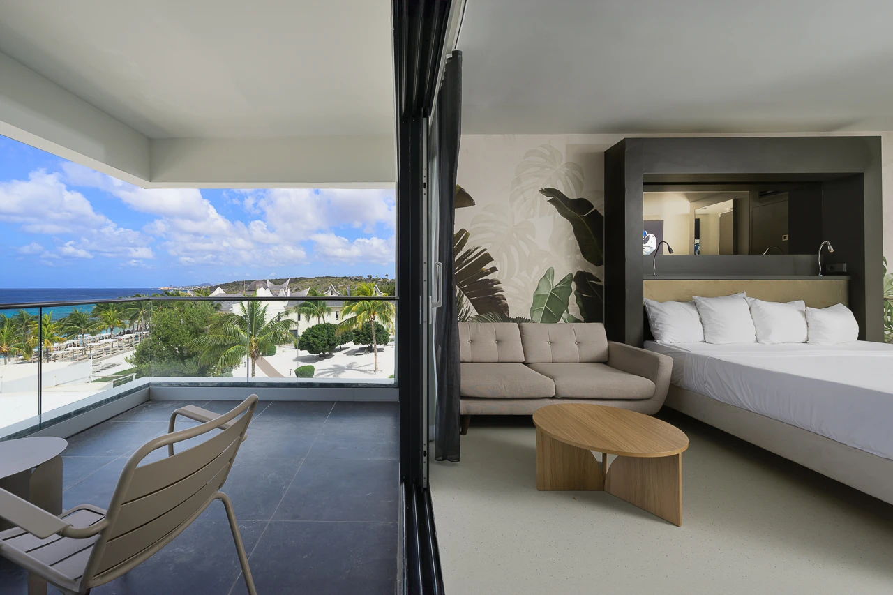 Modern suite at Papagayo Beach Hotel featuring a spacious balcony with ocean views, a plush bed, and contemporary tropical décor.