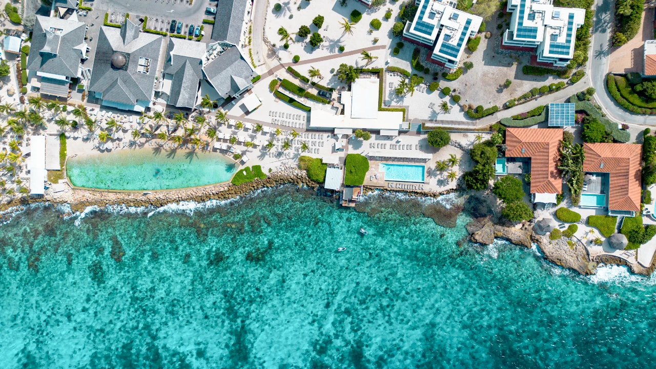 Papagayo Beach Hotel Sorroundings Stunning top-down shot of Papagayo Beach Club’s lagoon, infinity pool, and coastline, framed by crystal-clear Caribbean waters. Showing Papagayo's surroundings.